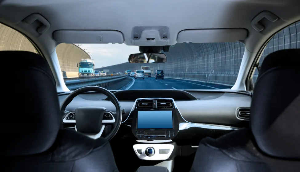 Cockpit of driverless car driving on highway viewed from rear seat.