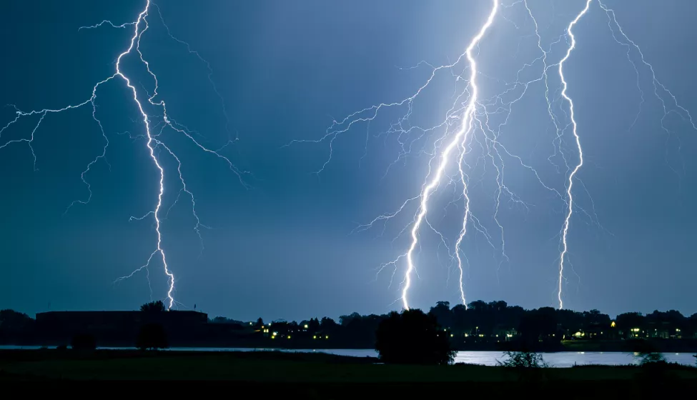 Lightning strikes community of homes in distance at night 
