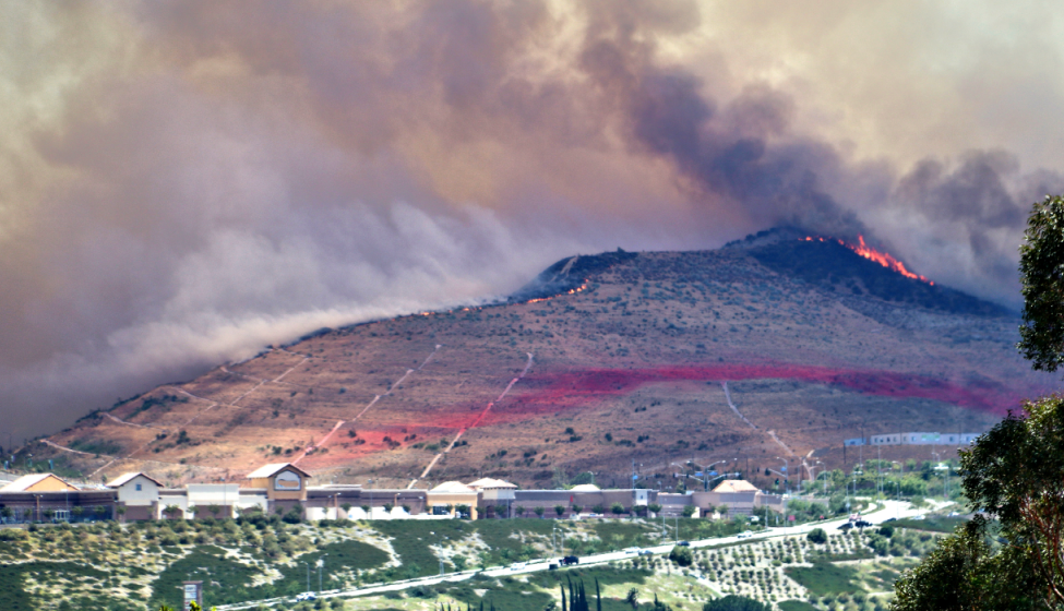 A controlled fire burns on the ridge of a foothill marked for fire management above a town
