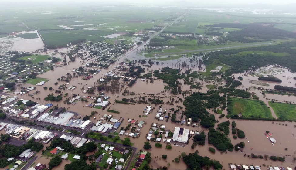 Aerial view of small town flooded with water after a storm with green fields in background 