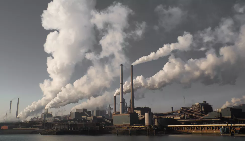 Industrial factories with billowing smokestacks along the docks near water's edge