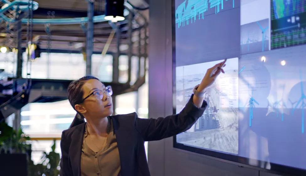 A scientist points to large screens and explains data
