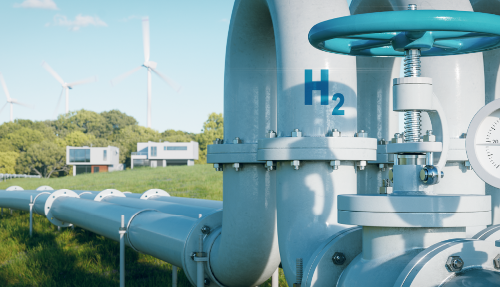 Hydrogen pipeline in a grassy field with wind turbines and buildings in the background
