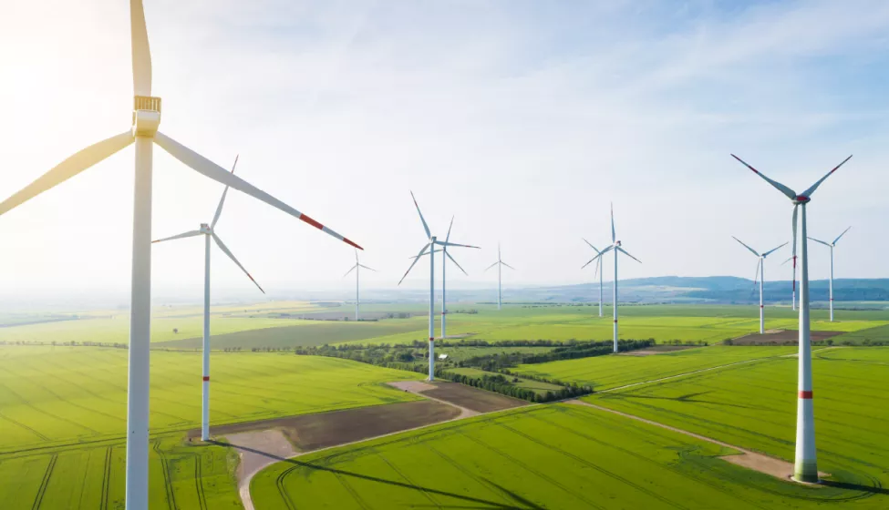 Multiple wind turbines blowing in the wind in a flat, green valley