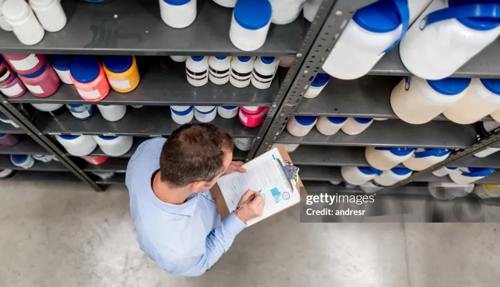 Man doing an inventory at a chemical warehouse and writing on a clipboard - business concepts