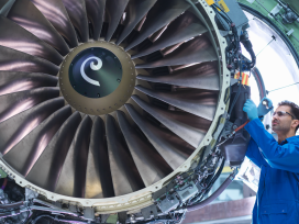 Aviation mechanic standing next to a large jet engine. Exponent provides aeronautical engineering expertise.