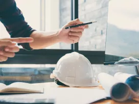 Construction consultant in an office meeting on cell phone, Exponent project management and schedule audits.