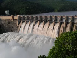 A large power generation dam, water rushing through open concrete gates on a river. Exponent utility and industrial power consulting.