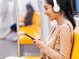 A person sitting in a train wearing headphones. Exponent helps manufacturers improve the quality and performance of consumer products.