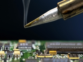 An expert analyzes a circuit board. Exponent engineers provide expert analysis of discrete components & printed circuit boards​