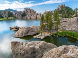 Beautiful natural landscape with boulders, a lake and trees. Exponent helps with environmental permitting.