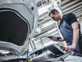 mechanic in uniform is working in auto service. Car repair and maintenance. Performing engine diagnostics